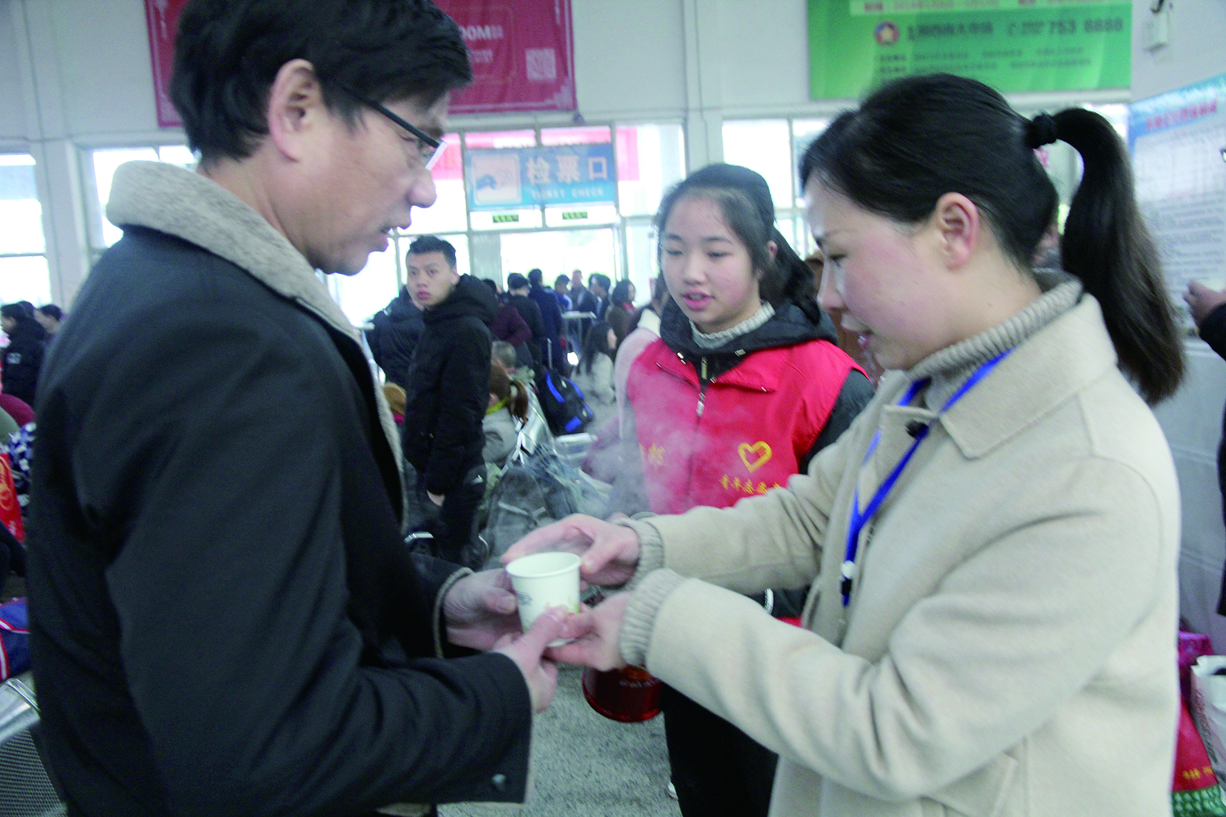 母女服務(wù)春運(yùn) 2月13日，記者在新邵分公司汽車站看到，該分公司安全科副科長李喜梅與其在新邵一中初中部1701班就讀女兒劉嘉怡在車站擔(dān)當(dāng)志愿者。李喜梅在候車室耐心為旅客釋疑解惑，劉嘉怡為旅客遞上一杯杯熱茶，有時(shí)母女也相互合作，其樂融融。 祖冠 攝影報(bào)道